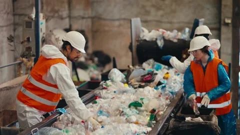 Shot from the side three workers in white uniforms in orange vests sort garbage 库存影片 266777182
