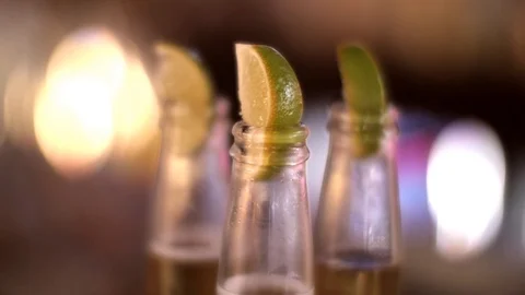 A shot of slices of lime in the top of bottles of beer Stock Footage 87857162