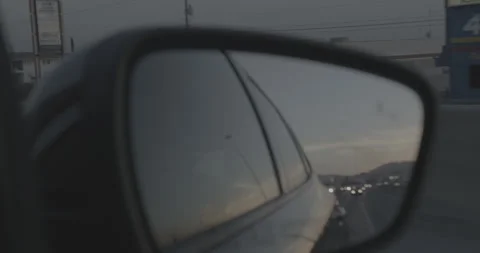 Shot of a Sunset Over a City Through a Car Mirror Stock Footage 246497409