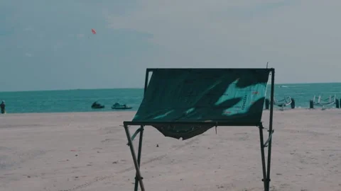 Shot of a temporary shade at beach with parasailing going on at background in Stock Footage 294486647