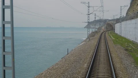 Shot from train window when railway goes into distance,sides sea and mountains Stock Footage 128240911