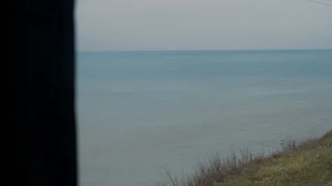 Shot from train window when railway goes into distance,on sides sea and grass Stock Footage 128241136