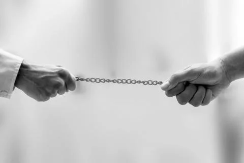 Shot of two hands on the end of a rusted metal chain pulling from both sides  Stock Photos