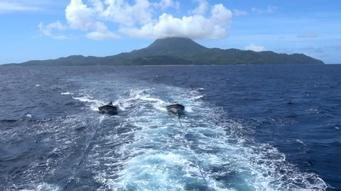Shot of two inflatable zodiacs pulled by ropes, volcano in background Stock Footage 111367630