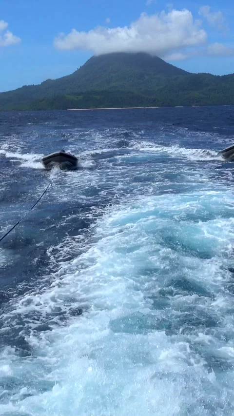 Shot of two inflatable zodiacs pulled by ropes, volcano in background Video stock 227803111