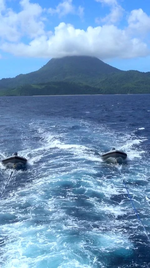 Shot of two inflatable zodiacs pulled by ropes, volcano in background Stock Footage 228828084