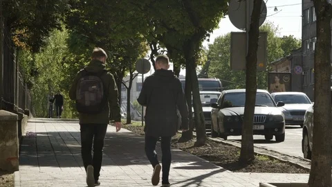 Shot of two man walking along the street, going away Vidéo 103340096