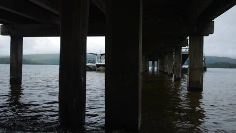 Shot under Pier on the beach looking out on the water with boats. Stock Footage 100572273