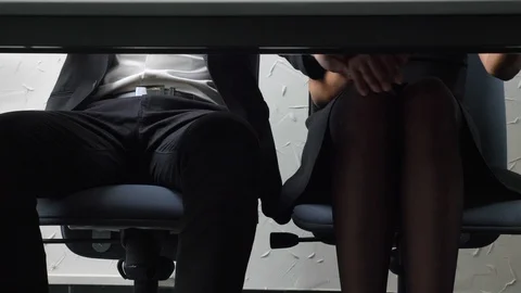 Shot under the table, a young boss girl touches his employee's foot, he opposite Stock Footage 89394936