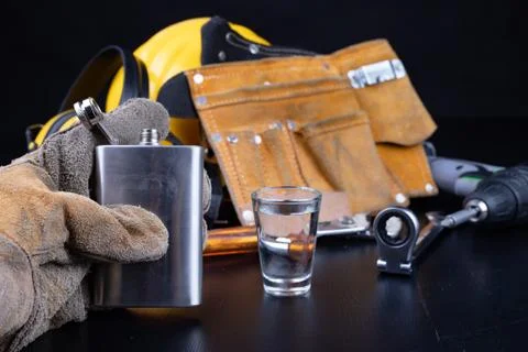 A shot of vodka and a bottle on a workshop table. Workwear and alcohol in the Stock Photos