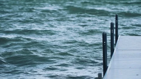 Shot of a white dock extending out into the water on a lake with choppy waves Vídeos de archivo 315168748