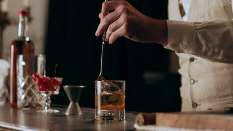 Shot of young classic styled bartender stirring the liquid in a glass with a lon Stock Footage 199459942