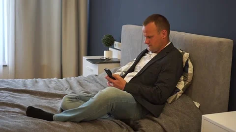 Shot of an young man is sitting on a bed and using a smart phone for send Stock Footage 164108553