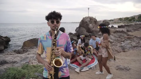 Shot of young saxophonist playing with group of friends having fun in background Stock Footage 243084113