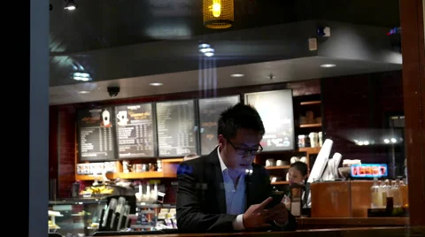 Shotting from outside window of customer buying coffee and checking cellphone Stock Footage 56528597