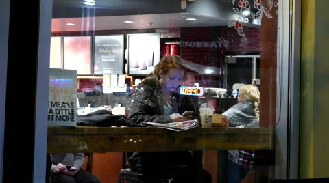 Shotting from outside window of customer checking cellphone message at Starbucks Stock Footage 57640733