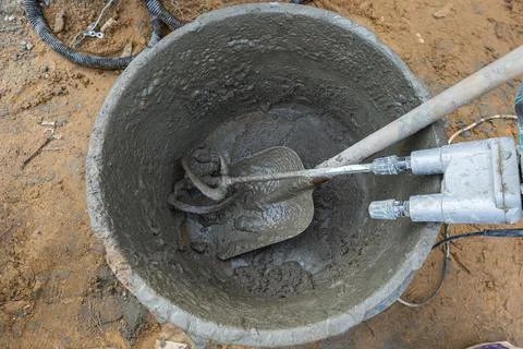 Shovel and mixer in a bucket in the process of preparing cement in construction Stock Photos