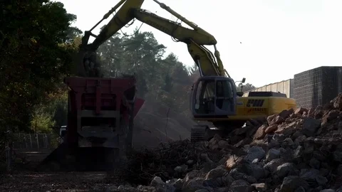 Shovel excavator taking up rocks, dumping rocks on the load bed of a truck Stock Footage 81456030