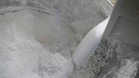 Shovel scooping crushed limestone pellets and white powder inside a bin at a Stock Footage 342896875