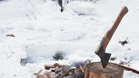A shovel throws snow next to an ax in a stump, slow motion, close-up Vídeos de archivo 234475256