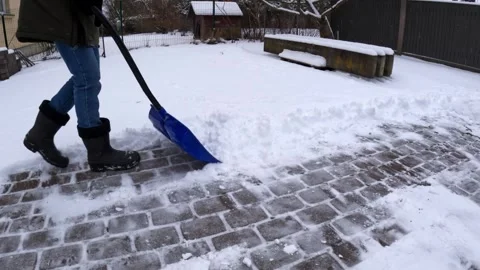 Shoveling Snow on a Brick Path in the Backyard during Winter Season Stock Footage 327554268