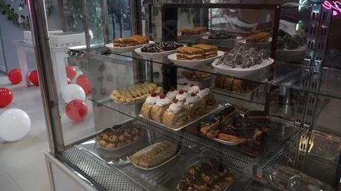 Showcase with different types of cakes and cookies in the shop window Stock Photos
