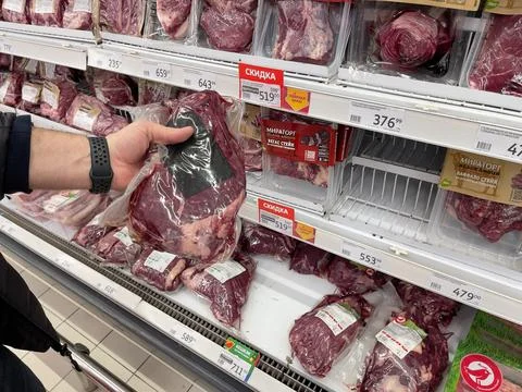 Showcase with marble beef. A piece of beef in a man's hand. Stock Photos