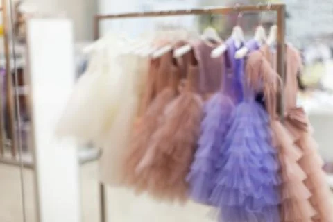 Showcase in store in defocus. Blurred view of beautiful ball gowns that hang Stock Photos