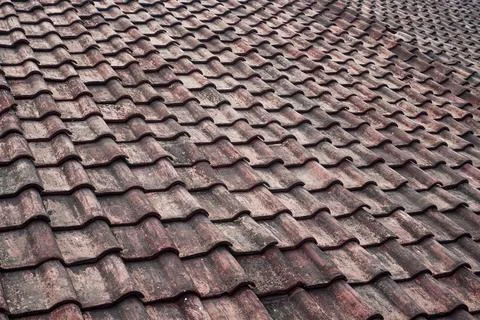 Showcasing a wide weathered interlocking s-shaped red clay tile roof layout. Stock Photos