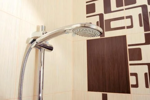 Shower on abstract brown tile background with ornament in bathroom 스톡 사진