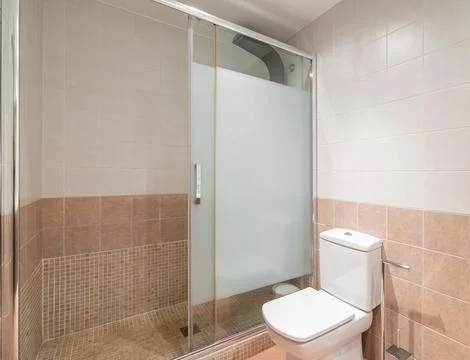 Shower area is separated from shared bathroom by sliding partition made of Stock Photos