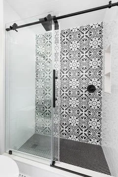 A shower with a black and white pattern tile. Stock Photos