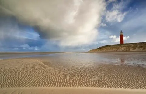 Shower cloud over coast with red lighthouse Stock Photos