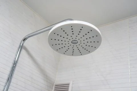 Shower head made of white plastic with a metal pipe on the background of a wh Stock Photos