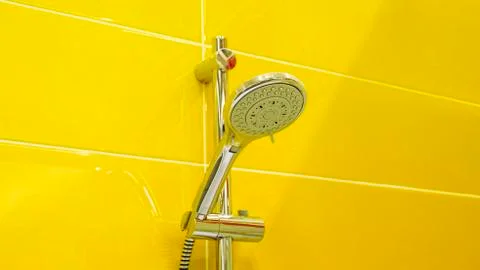 Shower head on tile wall texture background of yellow ceramic tile wall. Room Stock Photos