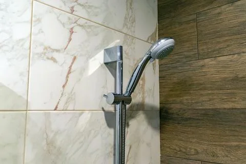 Shower head on the wall of ceramic tiles in the bathroom Stock Photos