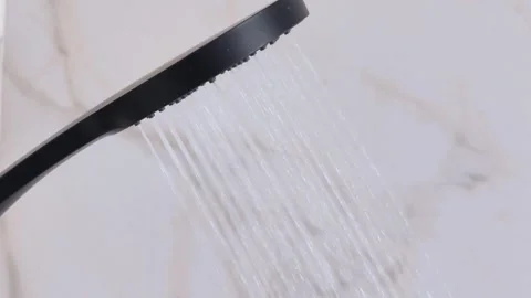 Shower head with water drops splashing out and running from faucet in bathroom. Stock Footage 316634624