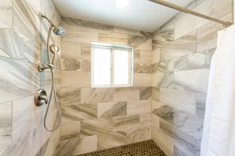 Shower stall interior with marble tile surround and small hexagon pattern tile Stock Photos