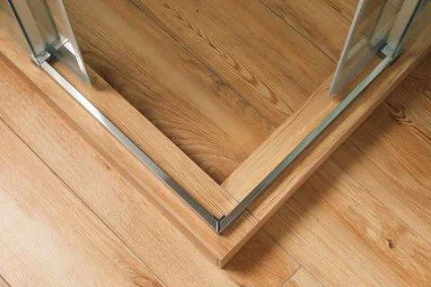Shower stall threshold. The floor is made of wood-look tile and the shower is Stock Photos