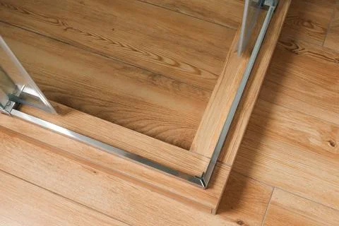 Shower stall threshold. The floor is made of wood-look tile and the shower is Stock Photos
