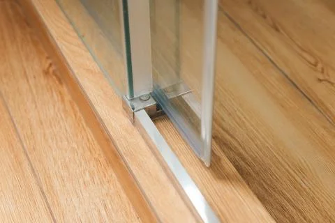 Shower stall threshold. The floor is made of wood-look tile and the shower is Stock Photos