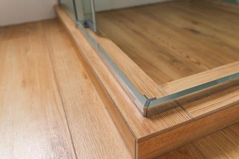 Shower stall threshold. The floor is made of wood-look tile and the shower is Stock Photos