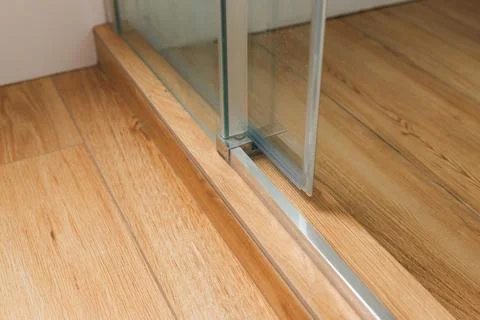 Shower stall threshold. The floor is made of wood-look tile and the shower is Stock Photos