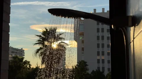 Shower stream with sunrise backdrop through window view with palm trees Stock Footage 295205638