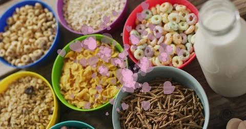 Showing array of bright cereal bowls filling wooden kitchen table, with milk jar Foto stock