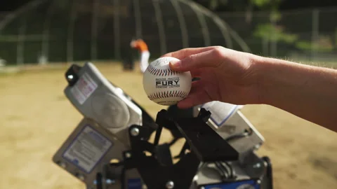 Showing the baseball by the pitching machine Stock Footage 304311246