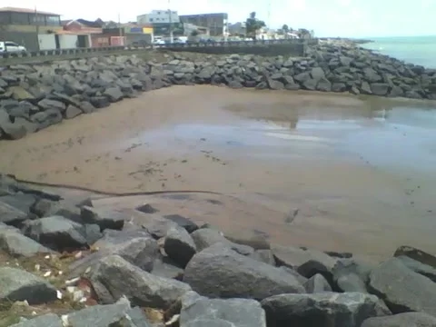 Showing the beach rocks right on the edge, there are cars on the track Stock Footage 163682781