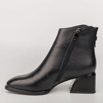 Showing a black ankle boot with a small heel and a zipper on the side, plac.. Stockfoto's