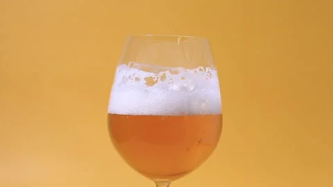 Showing a glass of beer close-up angle on yellow background Stock-Footage 197454434
