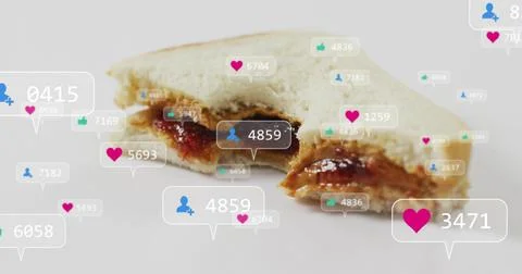 Showing half-eaten white bread sandwich oozing jam and brown spread on tabletop Stock Photos